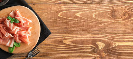 Board with slices of delicious jamon on wooden background with space for textの写真素材