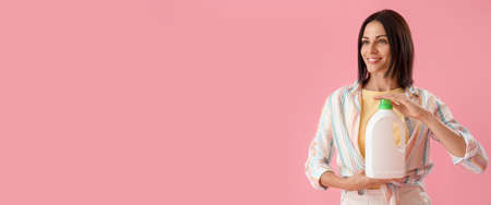 Young woman with detergent on pink background with space for textの写真素材