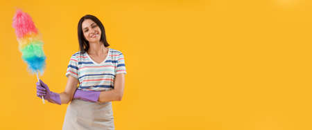 Young woman with pp-duster on yellow background with space for text