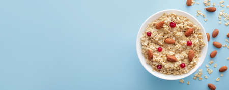 Bowl of tasty sweet oatmeal with nuts on light blue background with space for text, top viewの写真素材