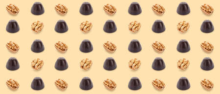 Many tasty chocolate candies and nuts on beige background. pattern for designの写真素材