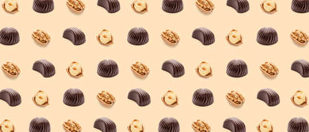 Many tasty chocolate candies and nuts on beige background. pattern for designの写真素材