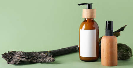 Bottles of natural shampoo and tree bark on green backgroundの写真素材