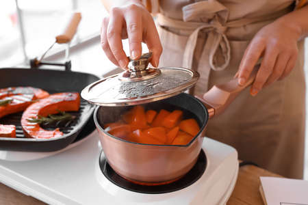 Young woman boiling pumpkin in kitchen, closeupの写真素材
