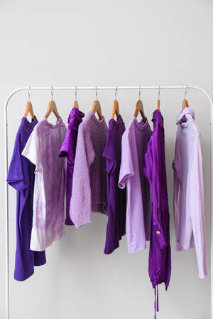 Rack with clothes in purple shades near light wallの写真素材