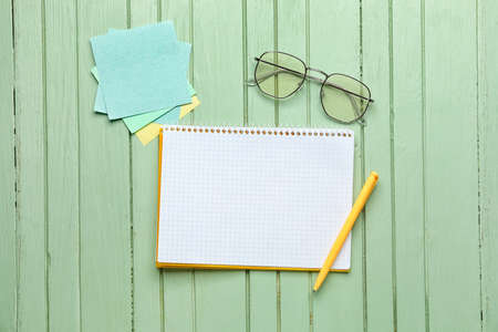 Notebook, pen, glasses and note papers on color wooden background, top viewの写真素材