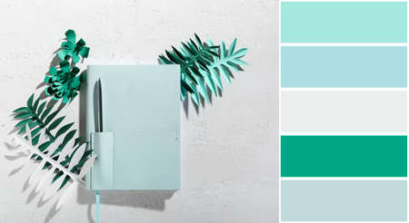 Stylish notebook with pen and paper palm leaves on white background. Different color patternsの写真素材