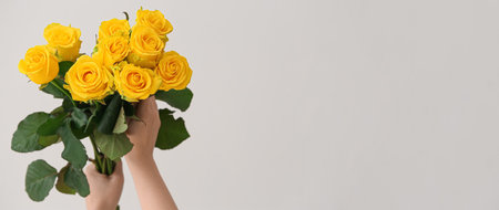 Hands holding bouquet of beautiful yellow roses on light background with space for textの写真素材