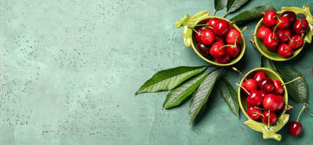 Bowls of tasty cherries on green background with space for text, top viewの写真素材
