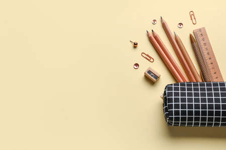 Pencil case with school stationery on color background
