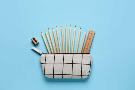 Pencil case with school stationery on blue background