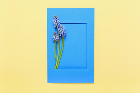 Frame with beautiful Muscari flowers on light yellow backgroundの写真素材