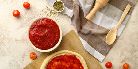Tasty tomato sauce and pizza dough on light background, top viewの写真素材