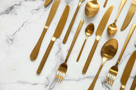 Many different golden cutlery on light marble background, top viewの写真素材