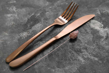 Golden cutlery and floral decor on grunge background