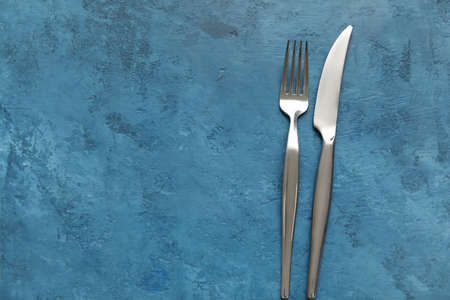Silver knife and fork on blue background