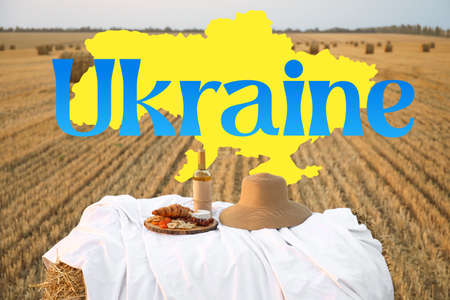 Picnic with tasty food and wine in harvested field and word UKRAINEの写真素材