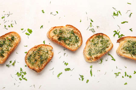 Slices of delicious toasted garlic bread with greens on light backgroundの写真素材