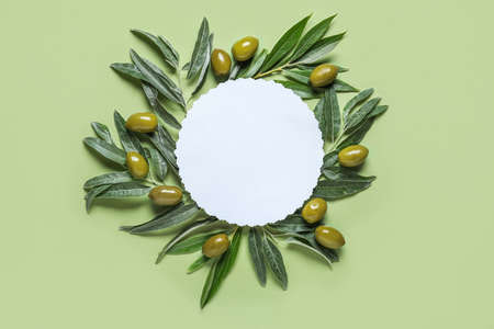 Blank paper sheet with green olives and leaves on color backgroundの写真素材