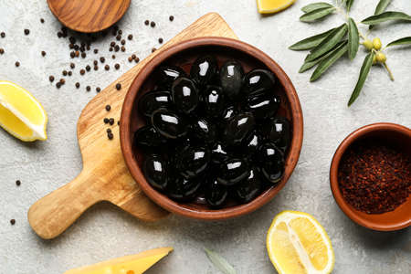 Composition with plate of tasty black olives, spices and lemon on light backgroundの写真素材