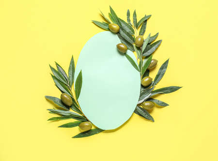 Blank paper sheet with green olives and leaves on yellow backgroundの写真素材
