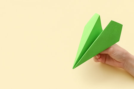 Woman with green paper plane on beige background, closeupの写真素材