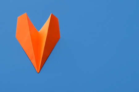 Orange paper plane on blue backgroundの写真素材