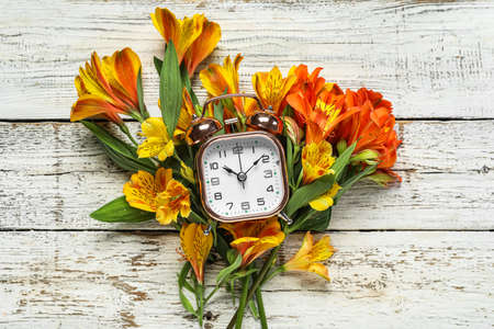 Composition with alarm clock and alstroemeria flowers on light wooden backgroundの写真素材