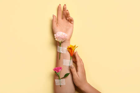 Woman with beautiful flowers and adhesive tape on beige backgroundの写真素材