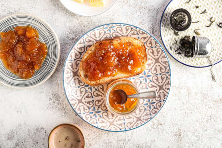 Plate with tasty toast, apricot jam and cup of coffee on grunge backgroundの写真素材