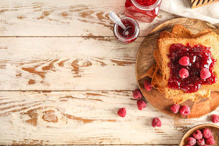 Plate with tasty toasts and raspberry jam on white wooden backgroundの写真素材