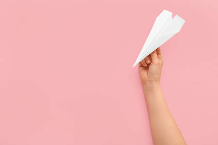 Woman with white paper plane on pink backgroundの写真素材