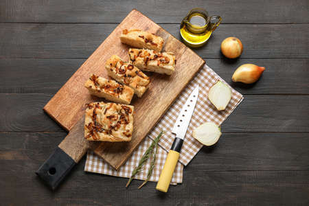 Composition with board of tasty Italian focaccia, onion and oil on dark wooden backgroundの写真素材