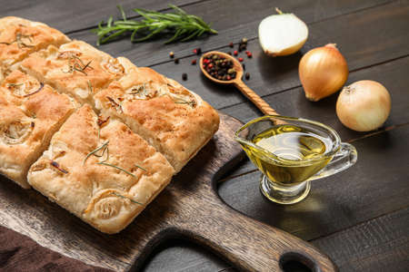 Board with tasty Italian focaccia and gravy boat of oil on dark wooden background, closeupの写真素材