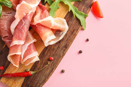 Wooden board with slices of jamon on pink background, closeupの写真素材
