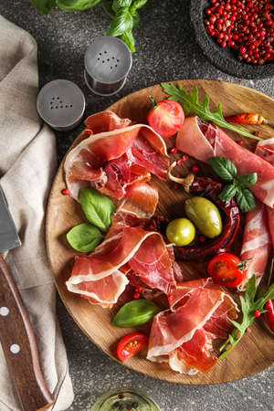Wooden plate with delicious jamon and spices on table, closeupの写真素材