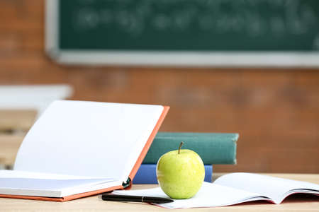 Apple with books on table in classroom