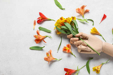 Composition with wooden hand and alstroemeria flowers on light backgroundの写真素材
