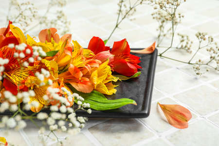 Board with beautiful alstroemeria flowers on light tile, closeup