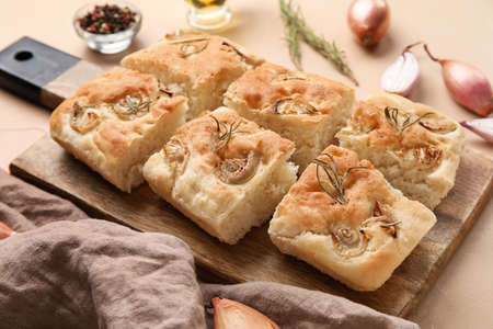 Wooden board with traditional Italian focaccia on color table, closeup