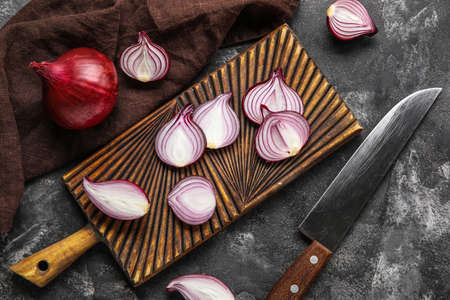 Composition with wooden board of cut red onion and knife on dark backgroundの写真素材