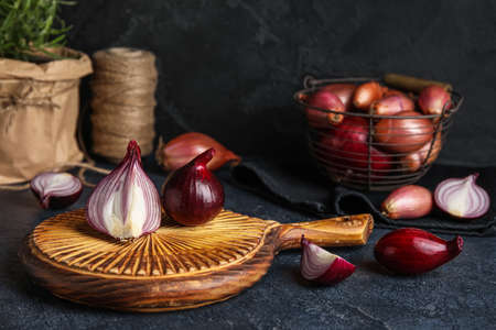 Wooden board with red onion on dark backgroundの写真素材