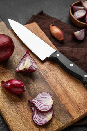 Wooden board with red onion on table, closeup