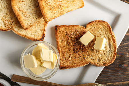 Plate with slices of toasted bread and butter on table, closeup