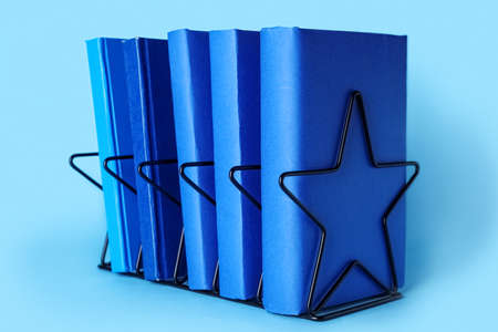 Black metal holder with books on blue backgroundの写真素材
