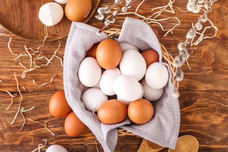 Bowl of white and brown chicken eggs on wooden background