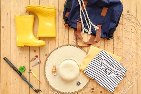 Accessories for traveling with fishing rod, net and floats on wooden background