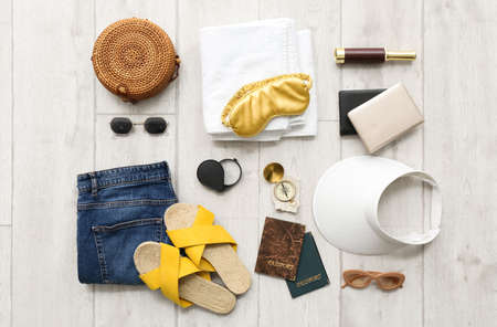 Female accessories for travel with compass on white wooden background
