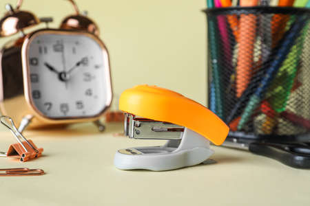 Stapler with stationery supplies and alarm clock on beige background, closeupの写真素材