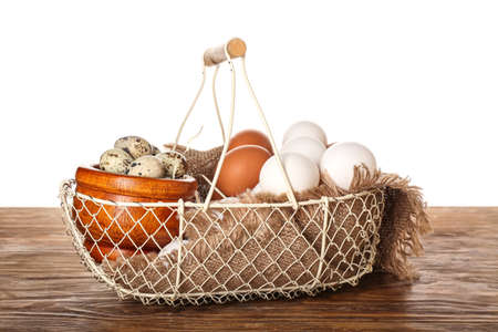 Basket with chicken and quail eggs on wooden table against white backgroundの写真素材